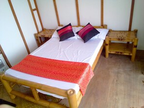 Ein Bett mit roter Decke, zwei Kissen und einem Holzkopfteil.