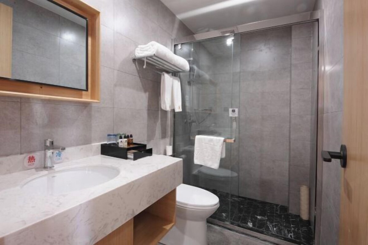 A modern bathroom with a marble sink, a glass shower enclosure, and a toilet.