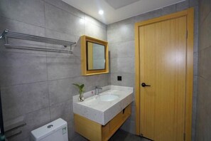 A bathroom with a wooden door, a white sink, a mirror, and a towel rack. - Zhongyou Holiday Hotel (Feidong)
