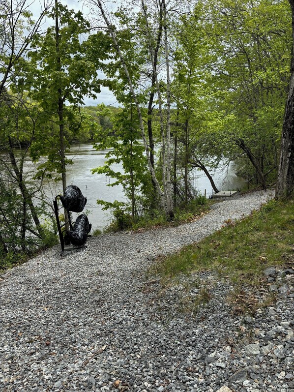 A gravel path beside a lake with trees and a bench. - Midcoast Maine Riverfront Sanctuary (Dresden)