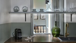 A kitchen with a coffee machine, a green bottle, and various glassware on shelves. - Athinaidos Divine Suite by K&K (Αθήνα)