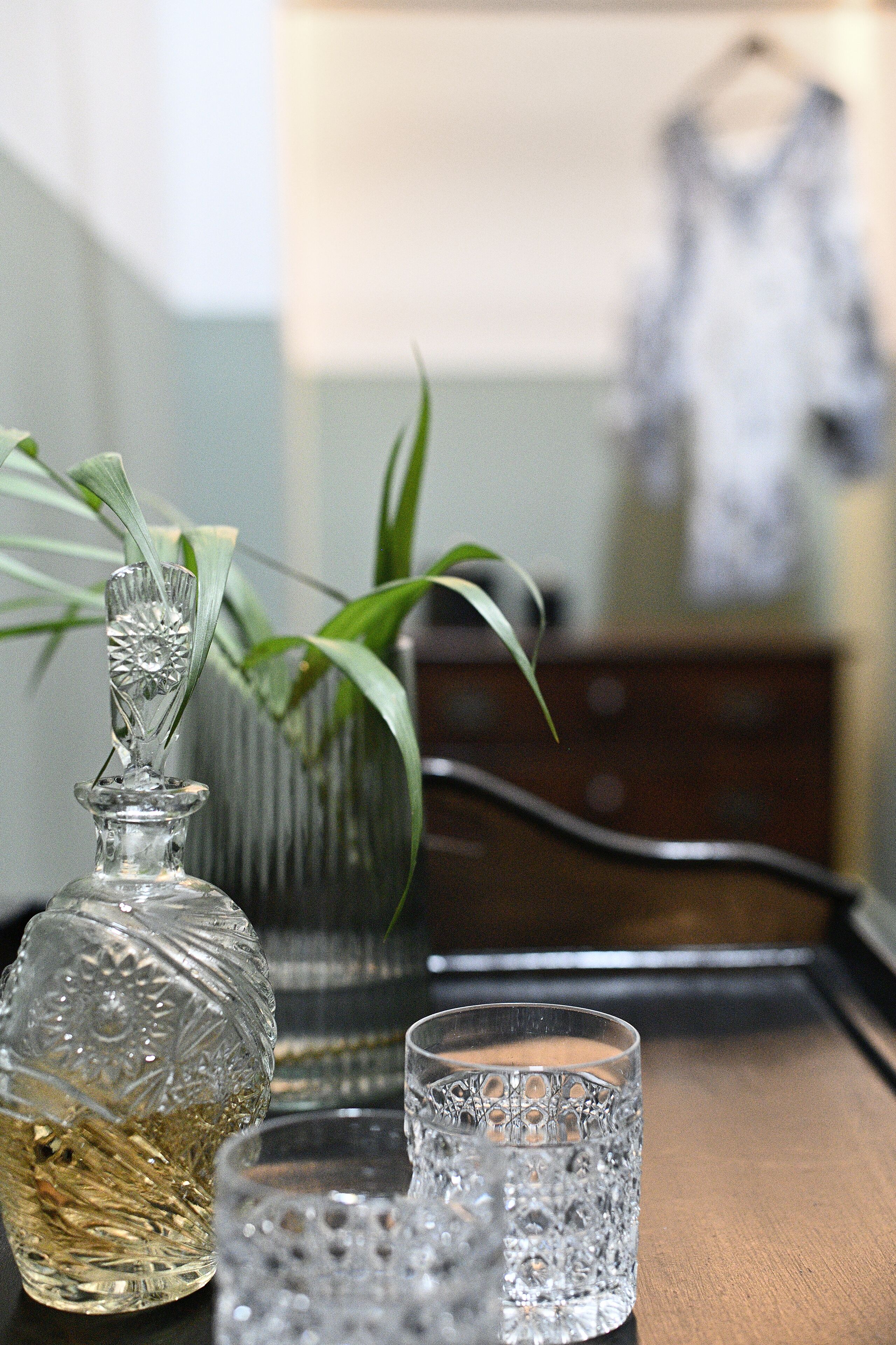 A glass decanter and two glasses on a wooden tray.