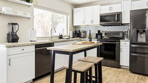 A modern kitchen with white cabinets, a granite countertop, a built-in oven, a microwave, and a stainless steel refrigerator. - PHX Scottsdale Oasis 4BR Private Pool Hot Tub Resort-Style Patio Shop Dine Golf (Phoenix)