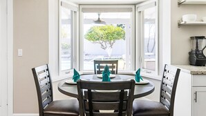 A dining area with a round table, chairs, and a view of the ocean through a window. - PHX Scottsdale Oasis 4BR Private Pool Hot Tub Resort-Style Patio Shop Dine Golf (Phoenix)
