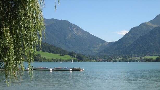 Un lac avec des bateaux, un quai et des montagnes en arrière-plan.