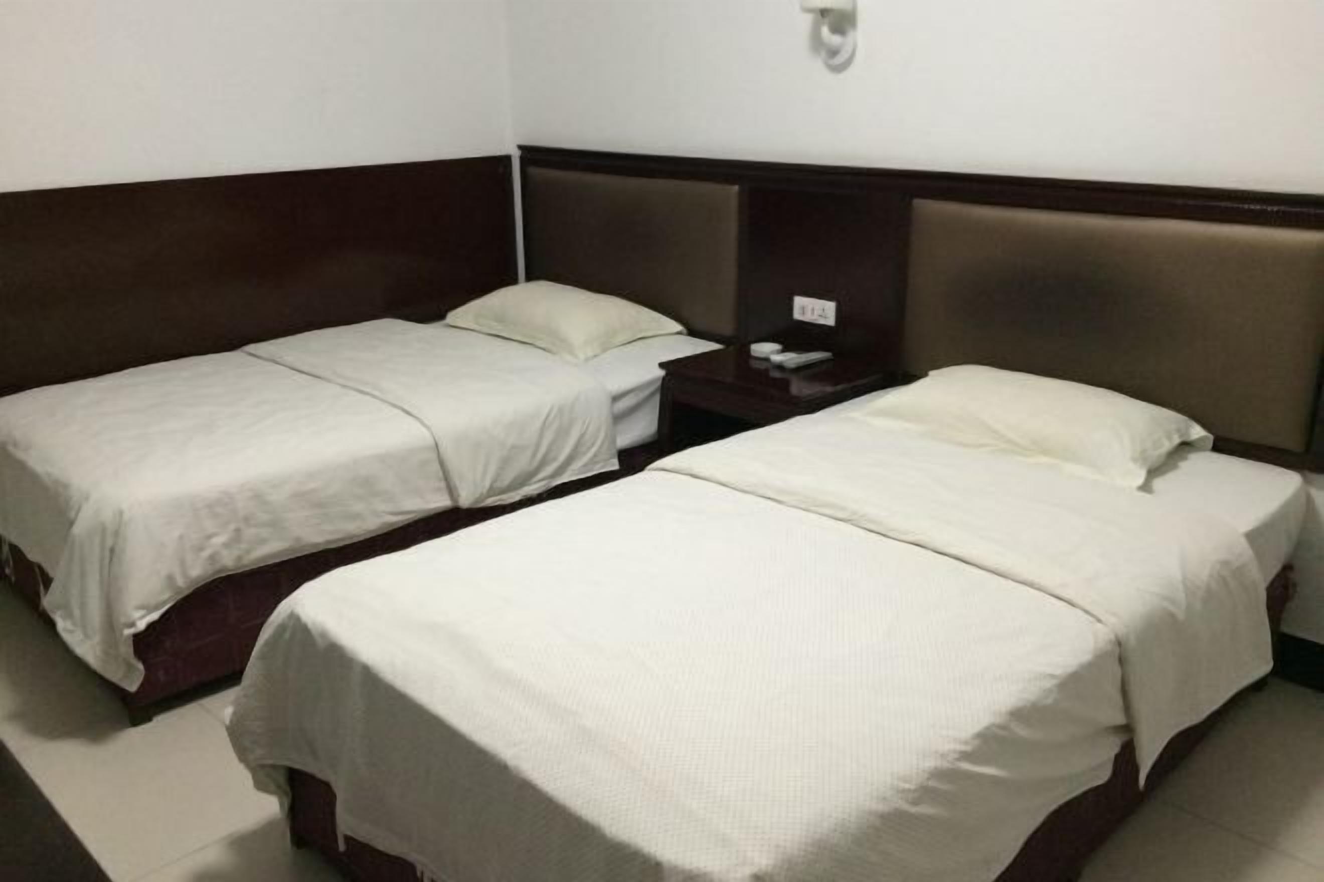 Habitación de hotel con dos camas individuales, una mesita de noche y una lámpara fijada a la pared.