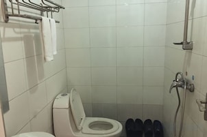 A small bathroom with a toilet, a shower, and a towel rack.