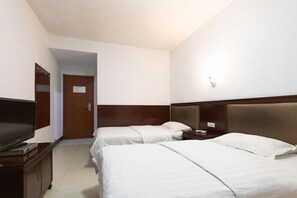 Habitación de hotel con dos camas, un televisor, una mesita de noche y una puerta que da a otra habitación.