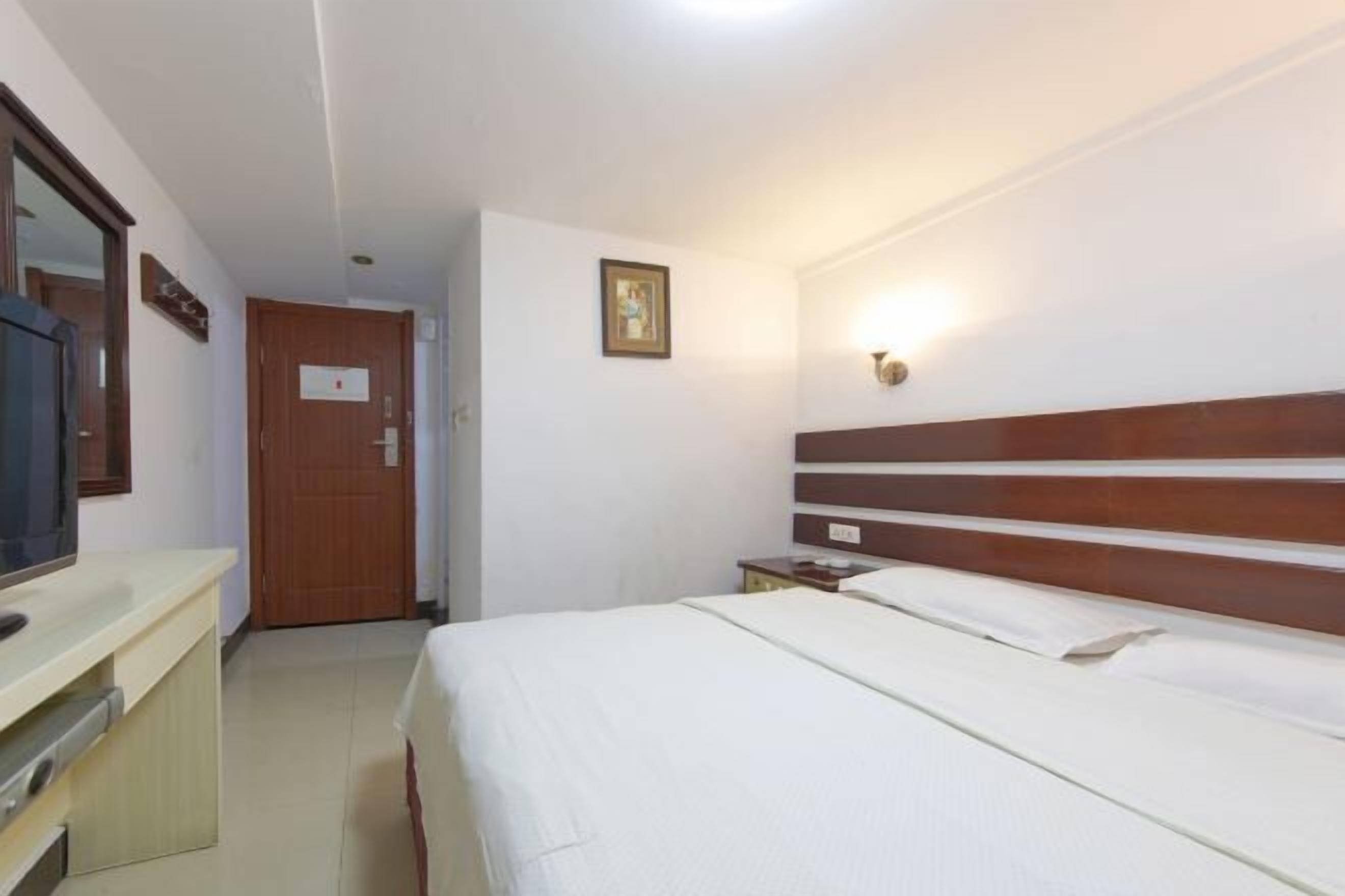 Ein Hotelzimmer mit Bett, Fernseher, Schreibtisch und Tür.