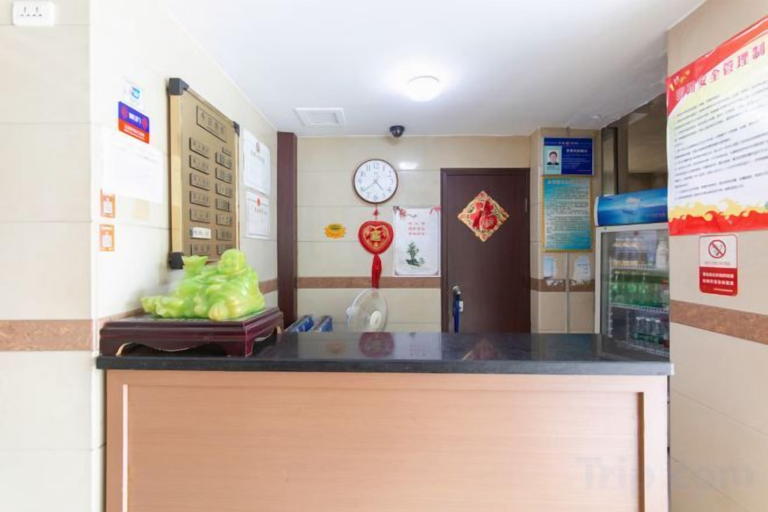 Un área de recepción con un mostrador de madera, un reloj en la pared y carteles informativos.