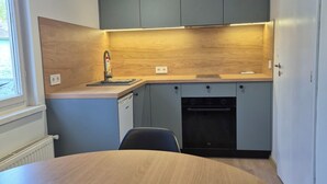 A modern kitchen with grey cabinets, a wooden countertop, and a built-in oven. - Hotel Elīna (Jurmala)