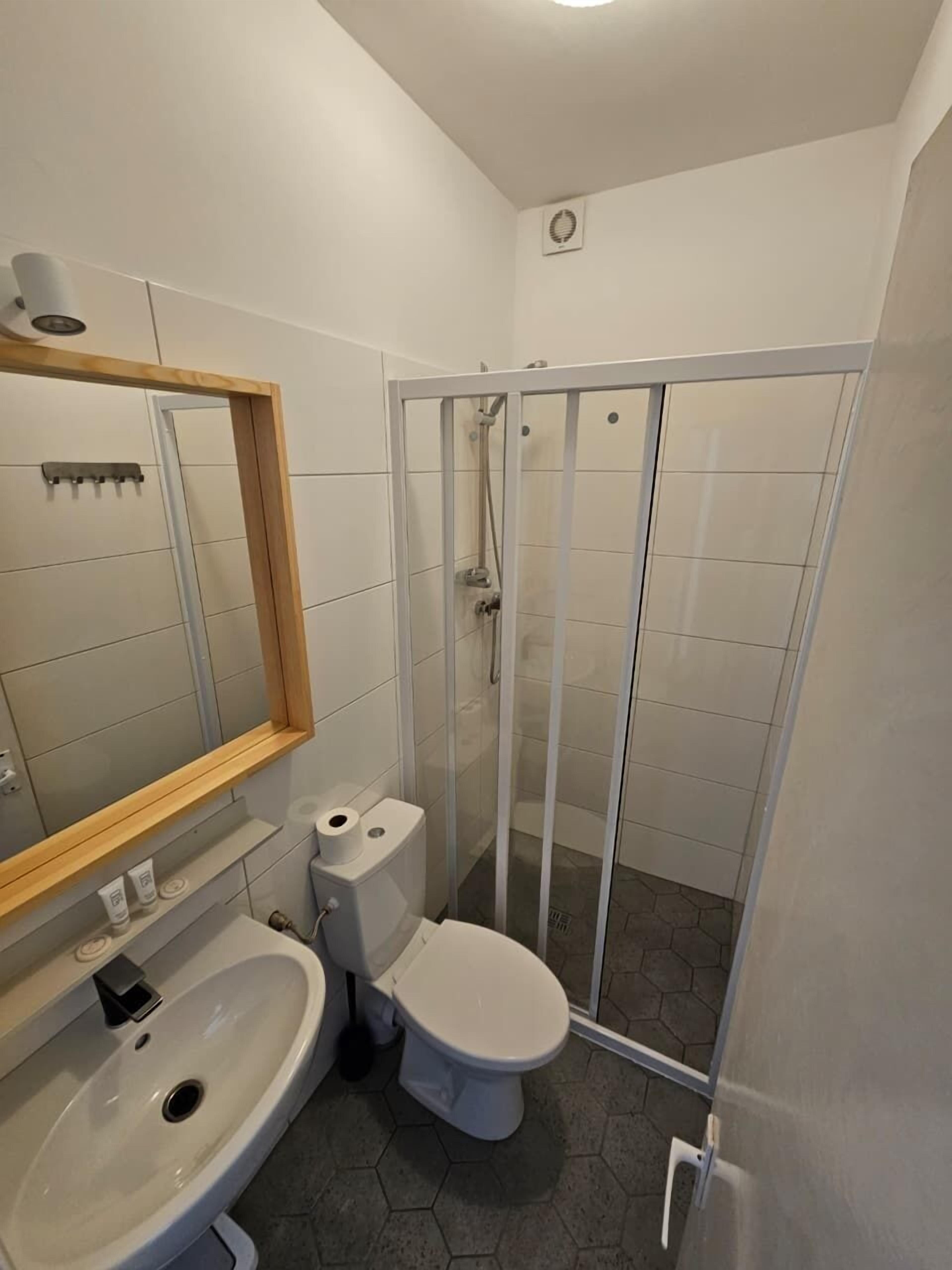 A bathroom with a toilet, sink, and shower enclosure.