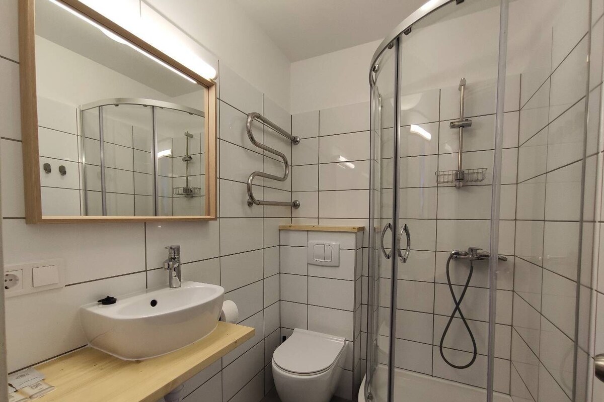 A modern bathroom with a white sink, toilet, and glass shower enclosure.