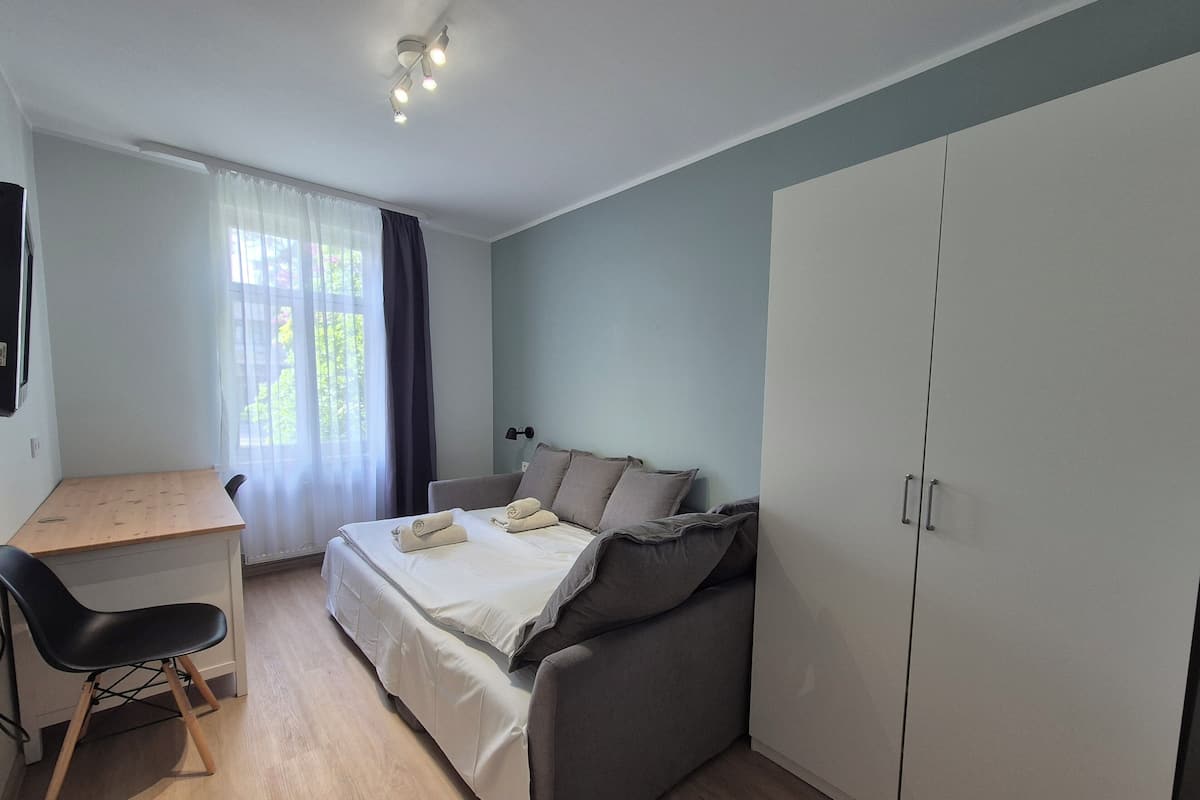 A bedroom with a bed, a desk, a chair, and a wardrobe.