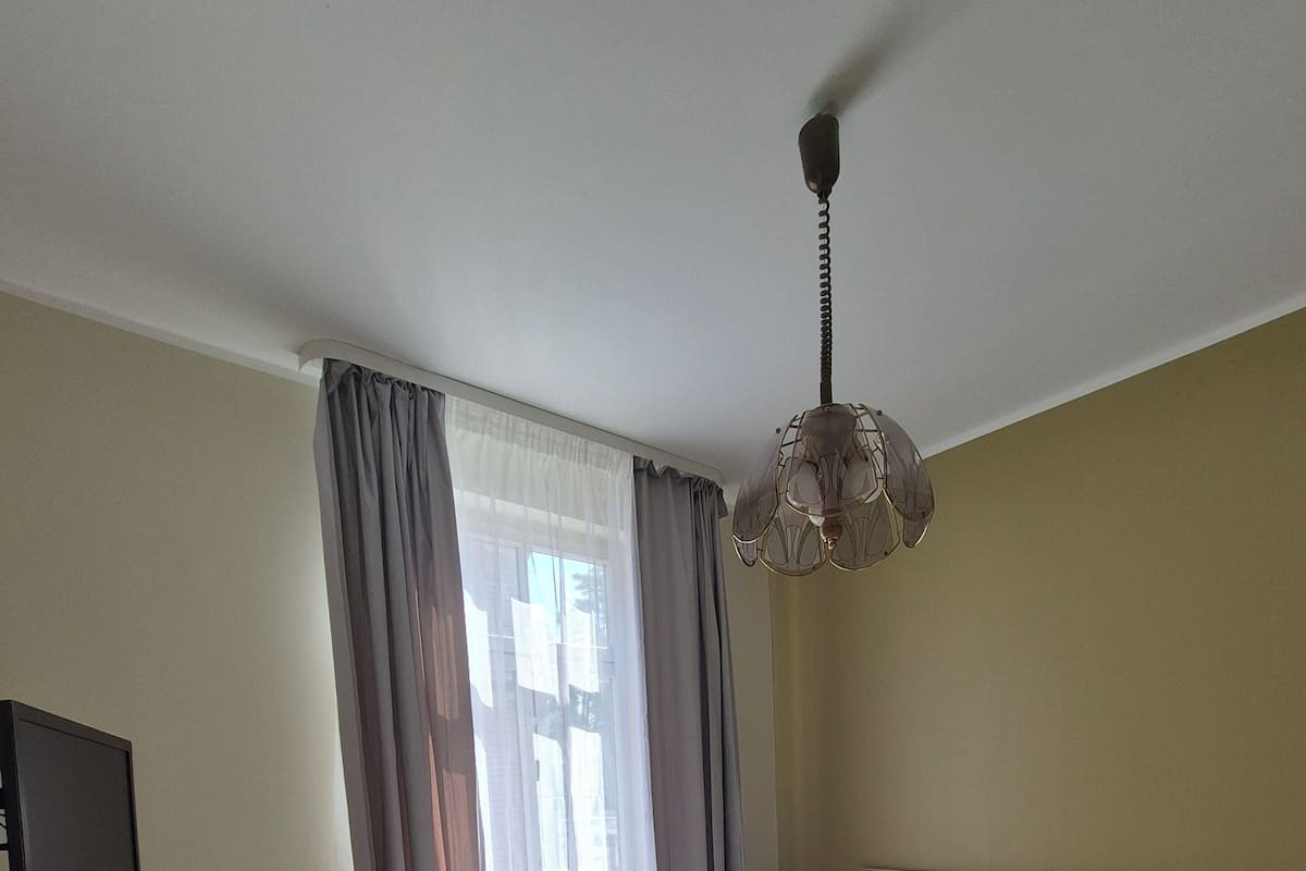 A hotel room with a bed, a desk, a chair, a TV, and a window with curtains.
