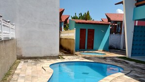 Ein Pool mit gebogener Form, umgeben von einer mit Fliesen ausgelegten Terrasse.