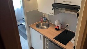 Een compacte keuken met een roestvrijstalen spoelbak, een inbouwoven en een vaatwasser.