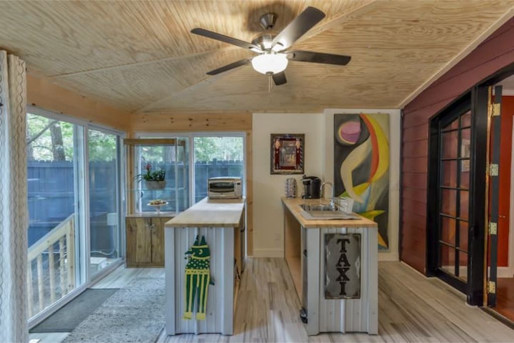 Cocina compacta con ventilador de techo, una pequeña isla y una puerta con la leyenda 'TAXI'.