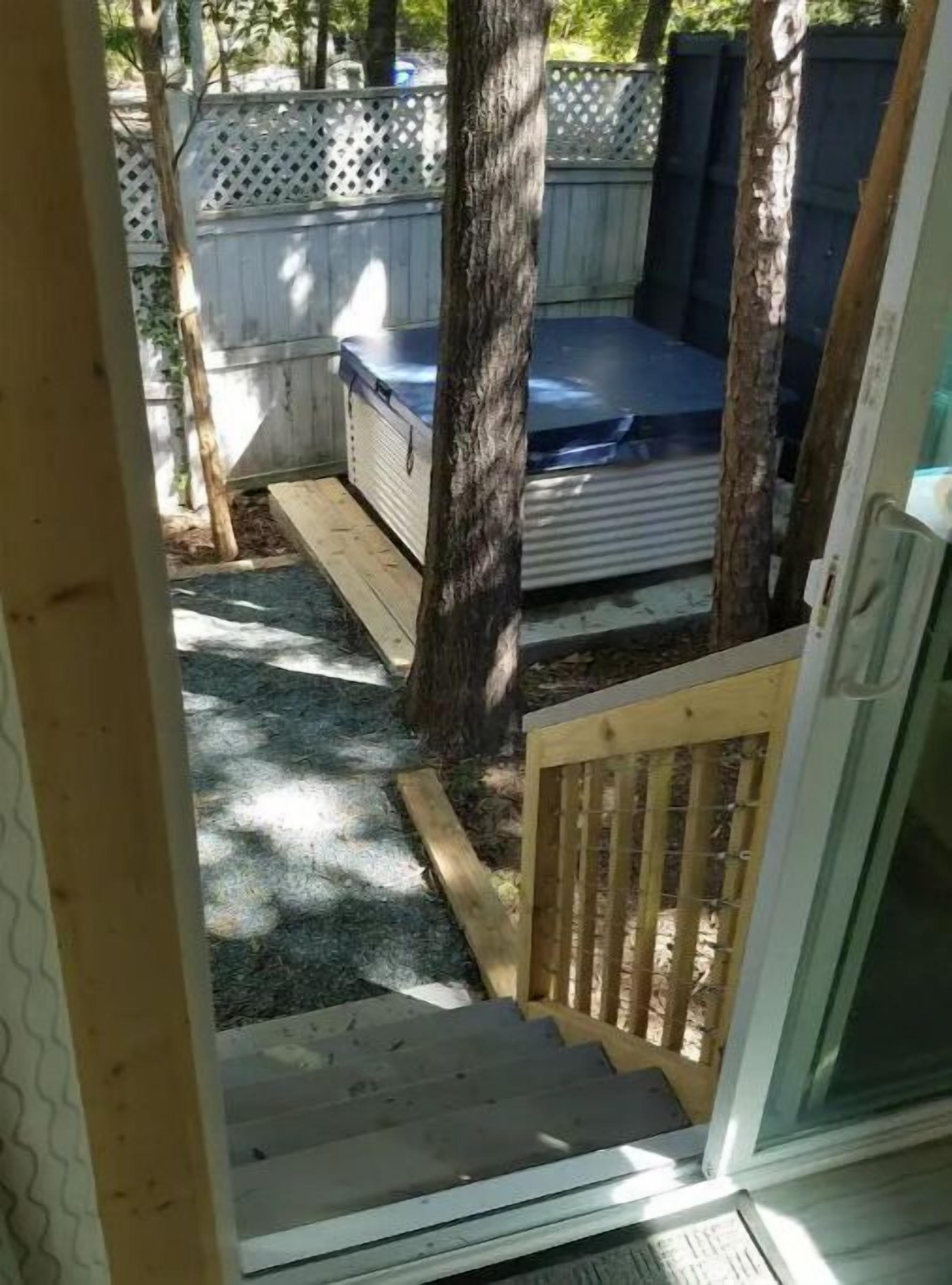 Eine Holzterrasse mit Whirlpool, einem Holzzaun und einem Baum.