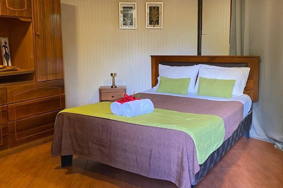 A bedroom with a wooden bed, a nightstand, and a wardrobe.