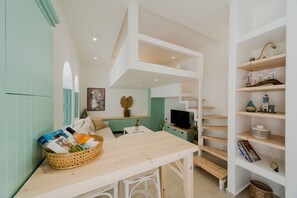 A modern interior with a wooden table, a basket of items, a television, and a bookshelf.