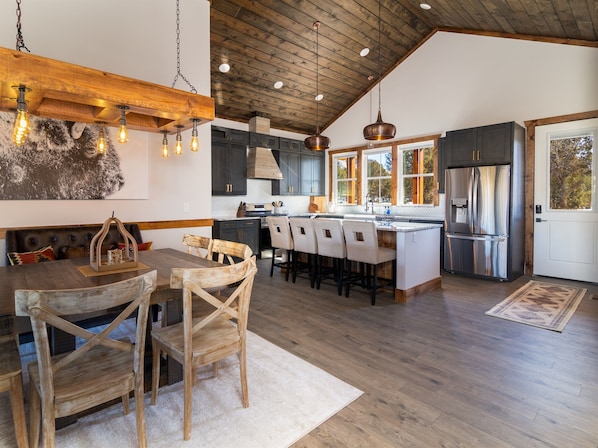 A modern kitchen with wooden beams, a central island, and a stainless steel refrigerator.