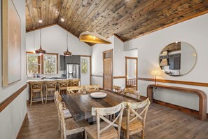 Un comedor amplio con una mesa y sillas de madera, una cocina con electrodomésticos modernos y un espejo grande en la pared.