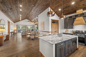 Un'ampia cucina con una grande isola, soffitto in legno ed elettrodomestici moderni.