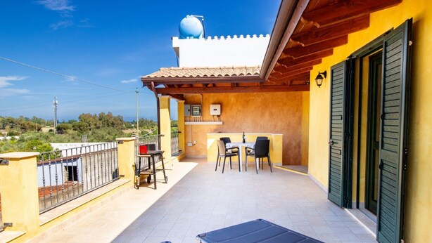 Un balcone con due sdraio, un tavolino con sedie e un serbatoio sull'edificio.