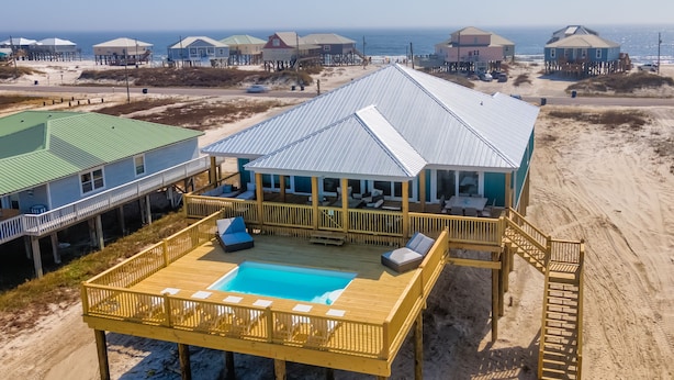 Una casa sulla spiaggia con piscina, terrazza e vista sull'oceano.