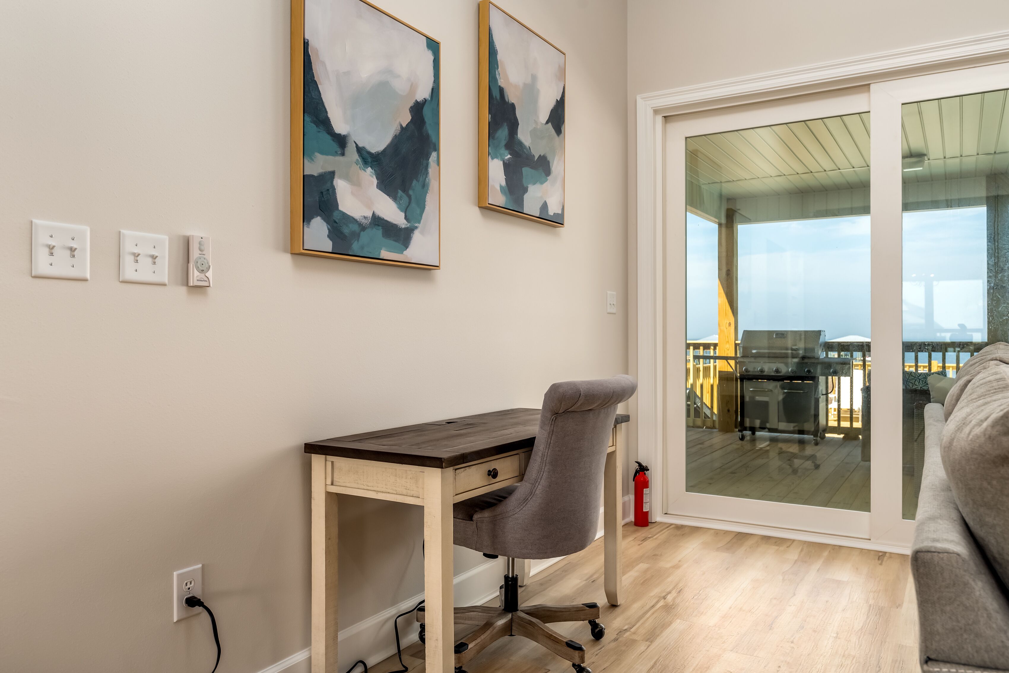 A modern room with a wooden desk, a grey office chair, and abstract art on the wall.