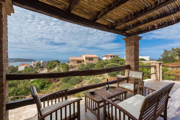 An outdoor patio with wooden furniture and a view of a coastal landscape.