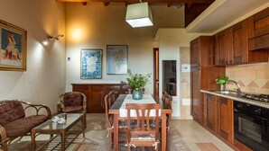 Un coin repas avec une table et des chaises en bois, un vase avec des plantes et un tableau au mur.