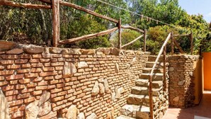 Un escalier en pierre menant à une structure en terrasses, avec une main courante en bois.