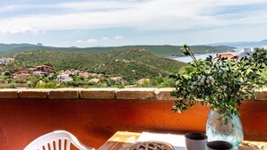 Un balcon avec une table, deux tasses et un vase rempli de fleurs.