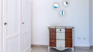Una habitación con un armario blanco, un tocador con la palabra 'HOME' encima y tres espejos en la pared.
