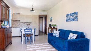 Una cocina moderna con armarios blancos, una mesa de comedor con sillas azules y un sofá azul con cojines decorativos.