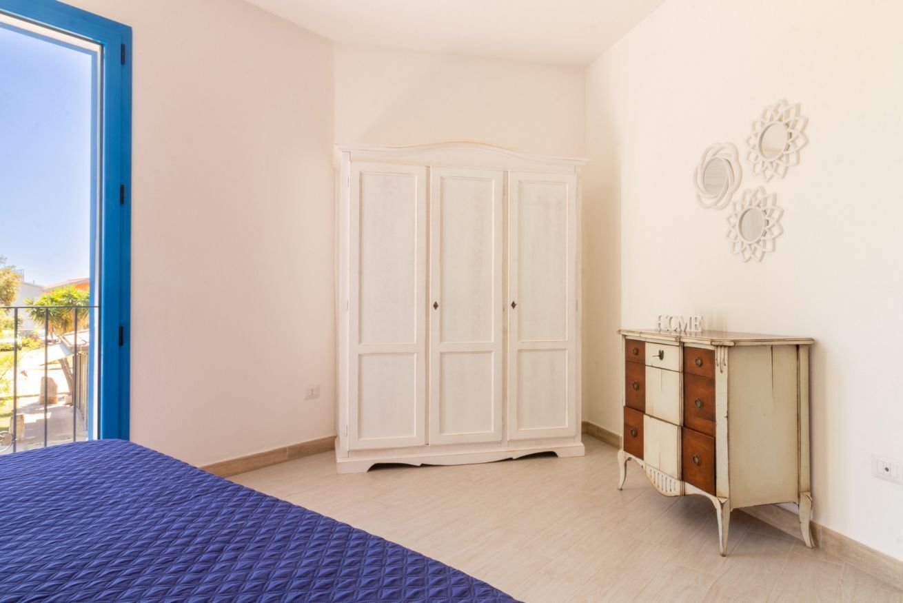 A bedroom with a bed, a wardrobe, and a dresser.