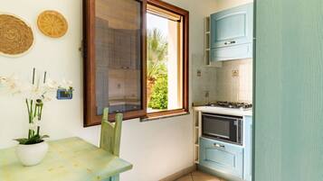 Eine kleine Küche mit Fenster, Herd und blauen Schränken.