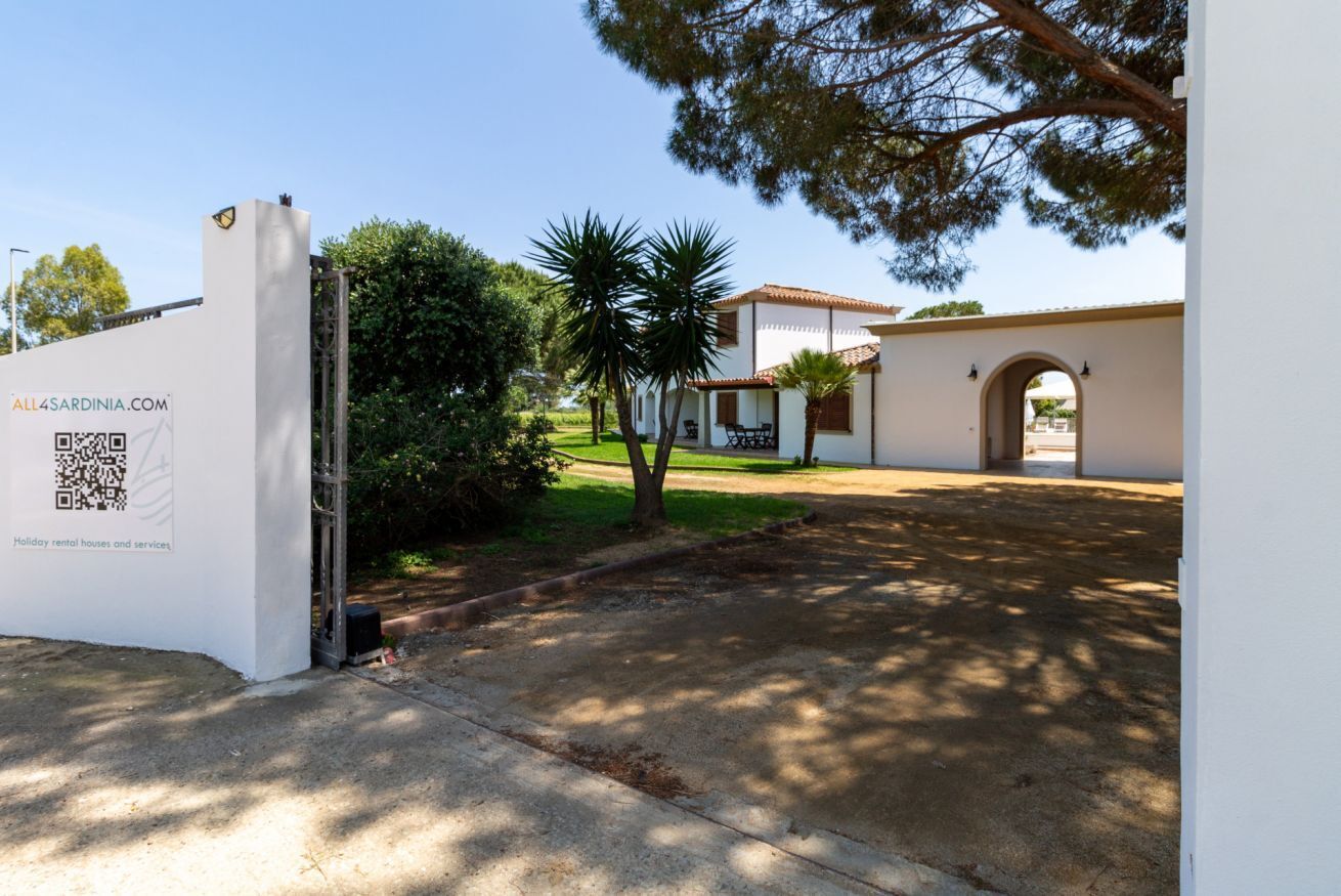 A gated entrance to a property with a white facade, a QR code, and a sign for holiday rental houses and services.