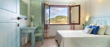Une chambre à coucher avec un lit, un bureau et une fenêtre donnant sur une colline.