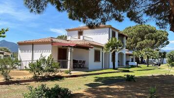 Una casa de dues plantes amb teulada de rajola, un balcó i una petita zona de pati.