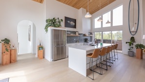 A spacious kitchen with a large island, wooden ceiling, and ample natural light.