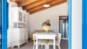 A dining area with a white table and chairs, a white cabinet, and a beige sofa. - Sole Apartment by All4sardinia  (Arbatax)
