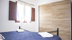 A bedroom with a bed, a wooden wardrobe, and a window with curtains.