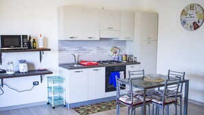 A compact kitchen with white cabinets, a microwave, a gas stove, and a dining area with a table and chairs.