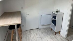 Une pièce de taille modeste, avec une table en bois, une armoire blanche et une horloge au mur.