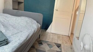 Une chambre à coucher avec un lit, une commode, un miroir et une porte.