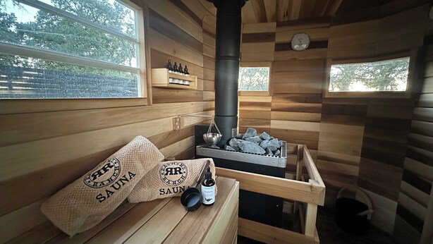 A sauna room with wooden walls, a large chimney, and a bench with towels.