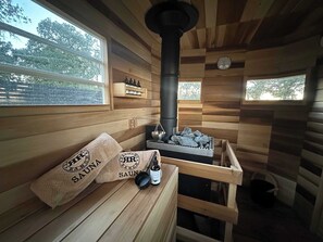 Un sauna aux murs en bois, doté d’une grande cheminée et d’un banc avec des serviettes.